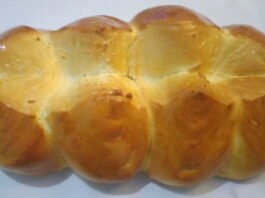 Foto de um pão sovado grande, dividido com um corte ao comprido e três cortes na vertical, formando oito gomos de pães.