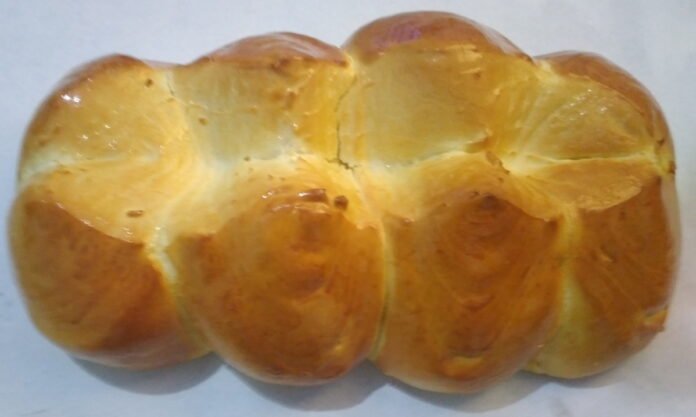 Foto de um pão sovado grande, dividido com um corte ao comprido e três cortes na vertical, formando oito gomos de pães.