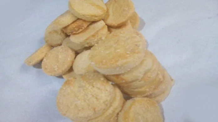 Moedinhas de queijo em pilhas, sobre um fundo branco e moldura preta.