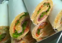 Sanduíche Marroquino Cinco sanduíches marroquinos. Uma espécie de rocambole com pão embrulhado em papel branco, recheado com presunto, queijo, pepino, alface e cenoura ralada. As pontas são expostas, mostrando o contraste dos cheios.